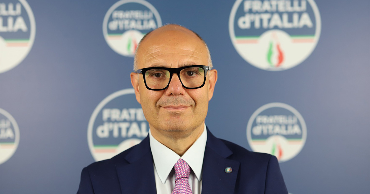 Ritratto di Raoul Russo davanti allo sfondo blu di Fratelli d’Italia